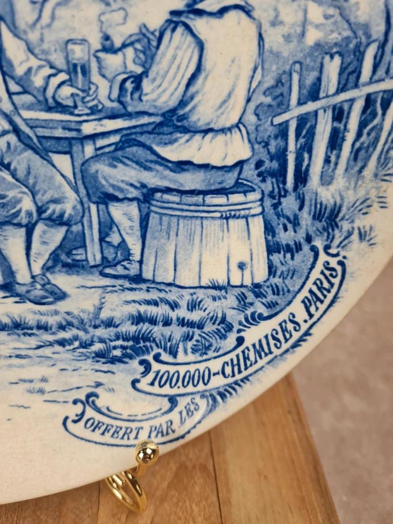 🍷 Assiette publicitaire ancienne décor bleu d’après Téniers – 100.000 Chemises Paris