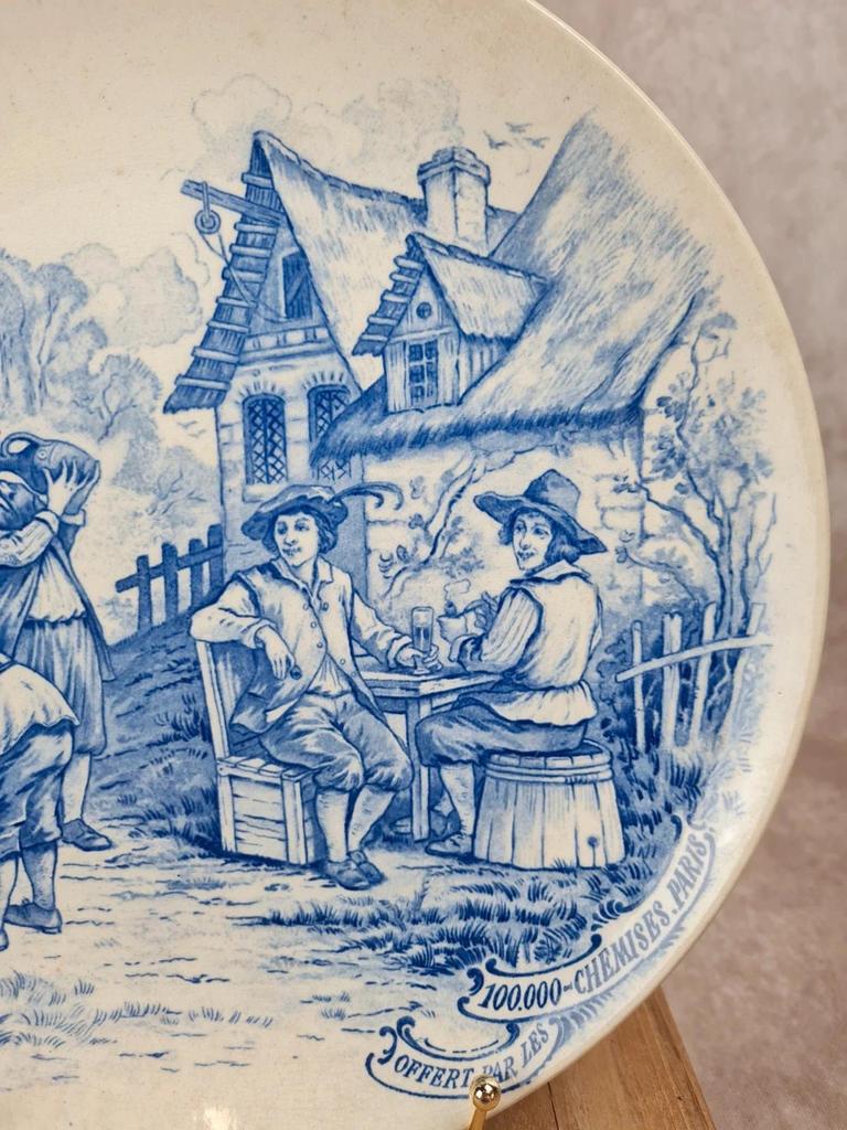 🍷 Assiette publicitaire ancienne décor bleu d’après Téniers – 100.000 Chemises Paris